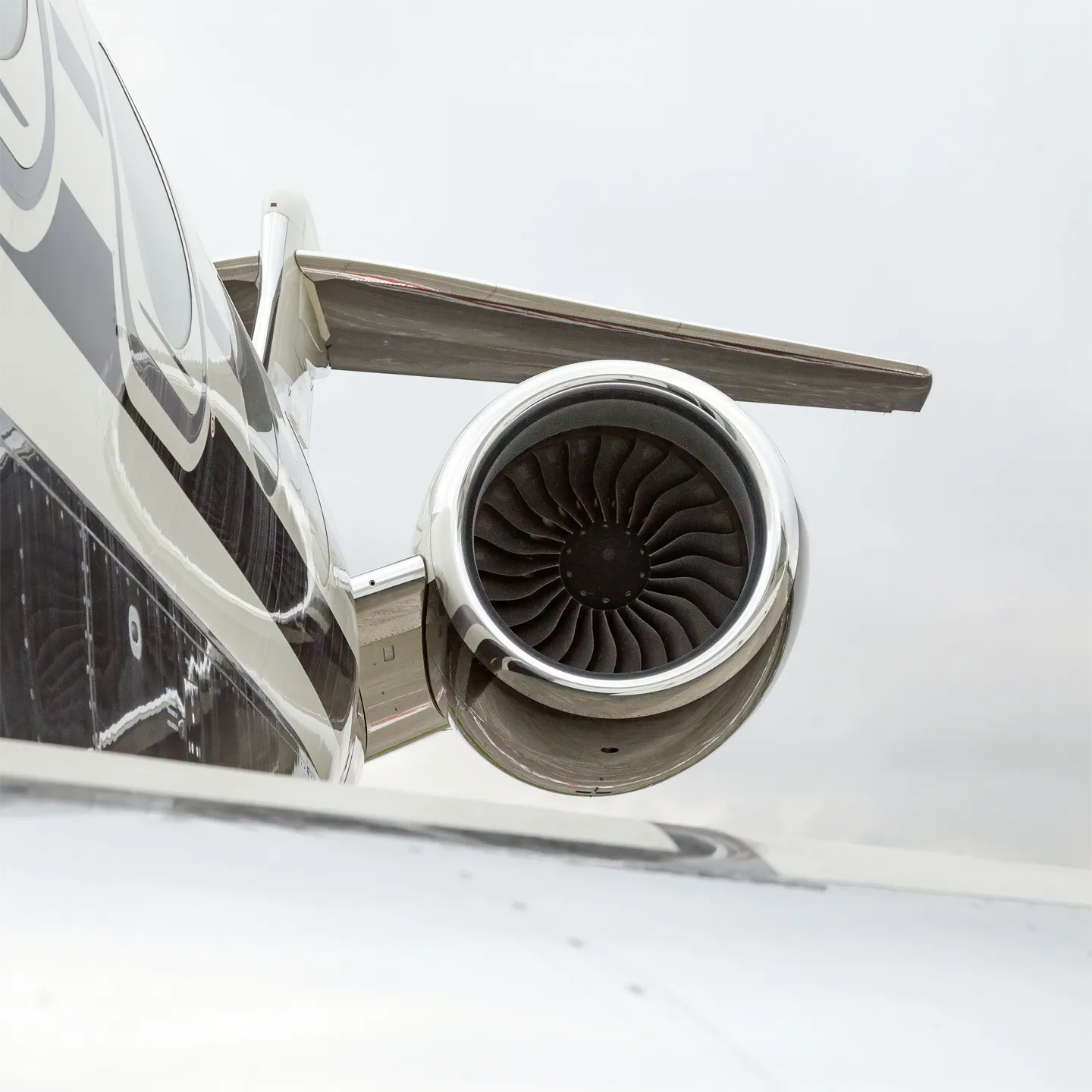 Close-up of the left engine on a Gulfstream G650, showing polished fan blades and a sleek black-and-white fuselage.